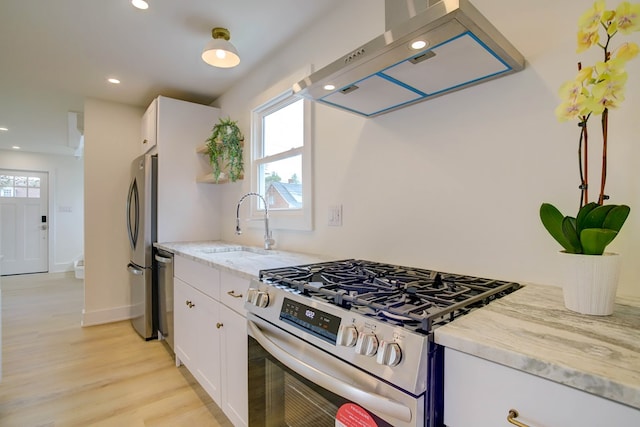 kitchen with white cabinets, recessed lighting, light stone counters, wall chimney range hood, and appliances with stainless steel finishes