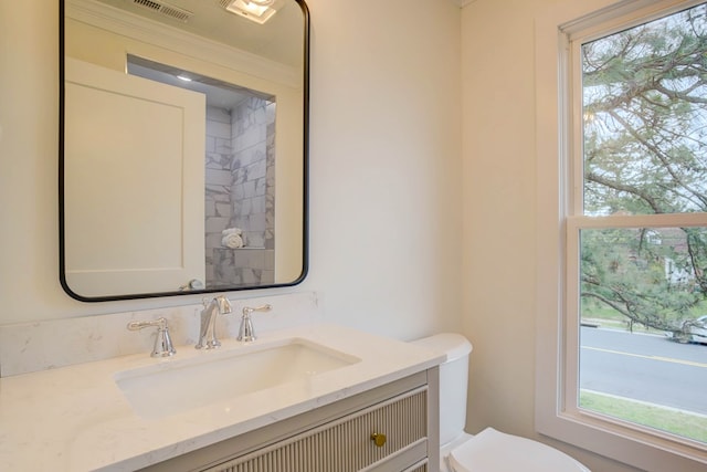 bathroom featuring toilet, a healthy amount of sunlight, vanity, and visible vents