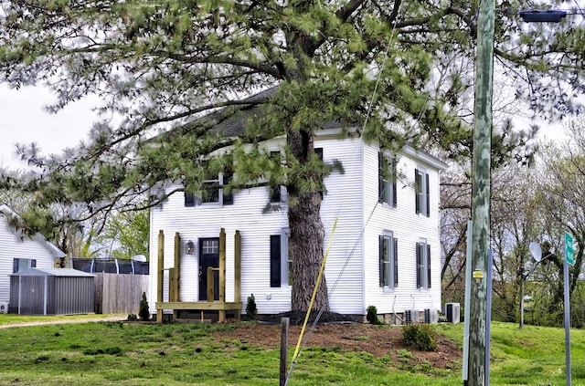 colonial home featuring a front lawn and central AC unit