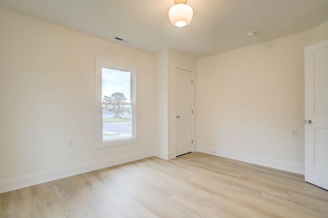 empty room featuring light wood-style floors, baseboards, and visible vents