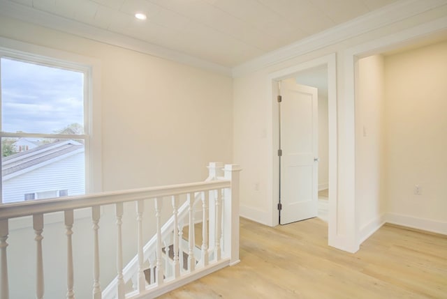 hallway featuring baseboards, ornamental molding, an upstairs landing, and light wood-type flooring