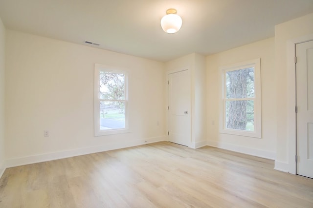 unfurnished room featuring light wood-style floors, baseboards, and visible vents