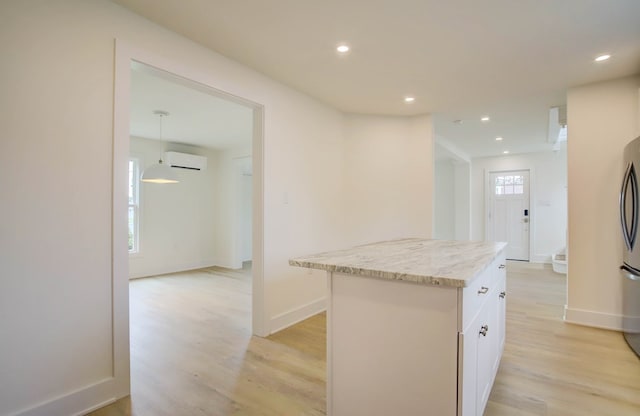 kitchen with light wood-type flooring, a center island, white cabinetry, and a wall unit AC