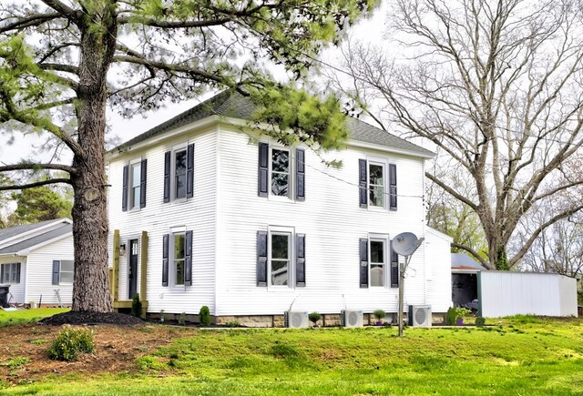 view of front of property featuring roof with shingles, ac unit, and a front yard