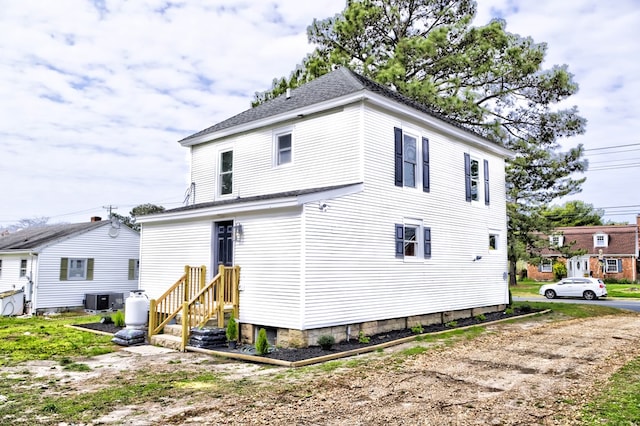 back of property with a shingled roof and central AC unit