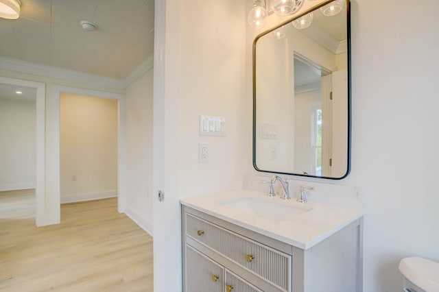 half bathroom featuring wood finished floors, toilet, vanity, and ornamental molding