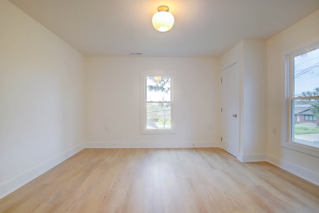 unfurnished room with light wood-style floors, plenty of natural light, and baseboards