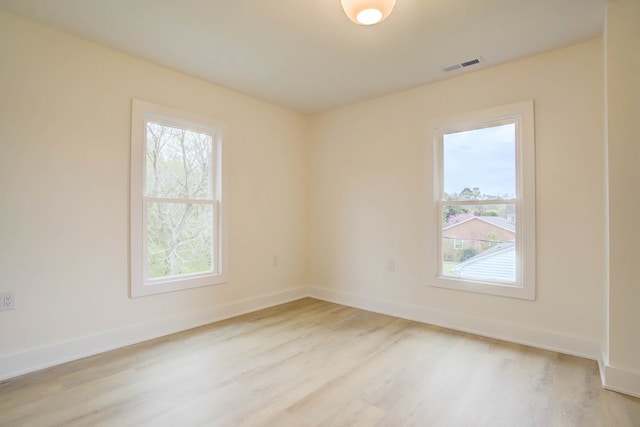 spare room featuring visible vents, baseboards, plenty of natural light, and light wood-style floors
