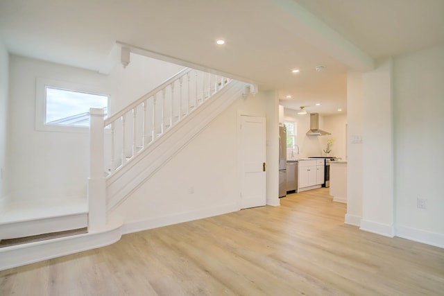 unfurnished living room featuring light wood finished floors, a wealth of natural light, and stairs