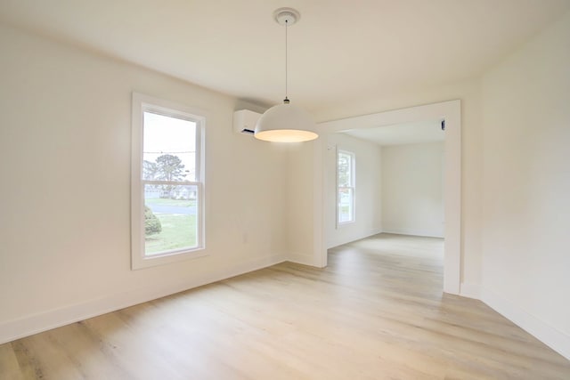 unfurnished room with a wealth of natural light, light wood-style flooring, and an AC wall unit