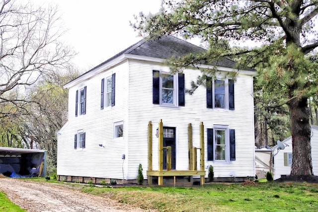 view of front of home with roof with shingles and a front lawn
