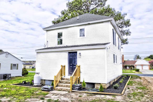 back of property with a shingled roof and central AC unit