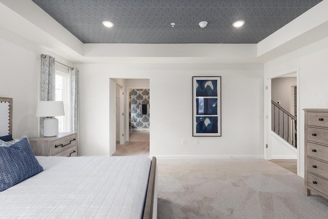 bedroom with a tray ceiling and light carpet