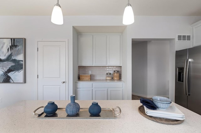 kitchen featuring decorative backsplash, white cabinetry, stainless steel refrigerator with ice dispenser, and hanging light fixtures