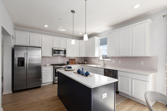 kitchen featuring a center island, sink, hanging light fixtures, white cabinetry, and stainless steel appliances