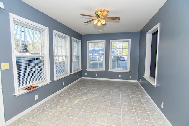 unfurnished sunroom featuring ceiling fan and a healthy amount of sunlight