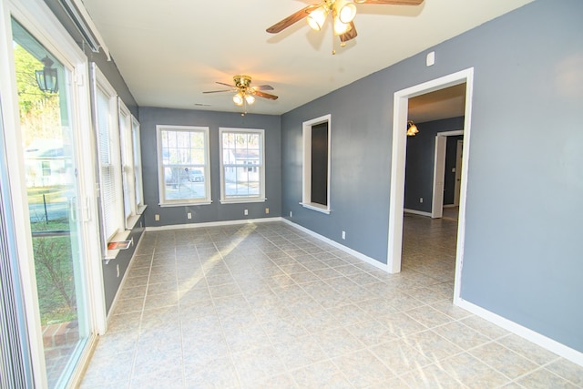 unfurnished room with plenty of natural light, light tile patterned flooring, and ceiling fan with notable chandelier