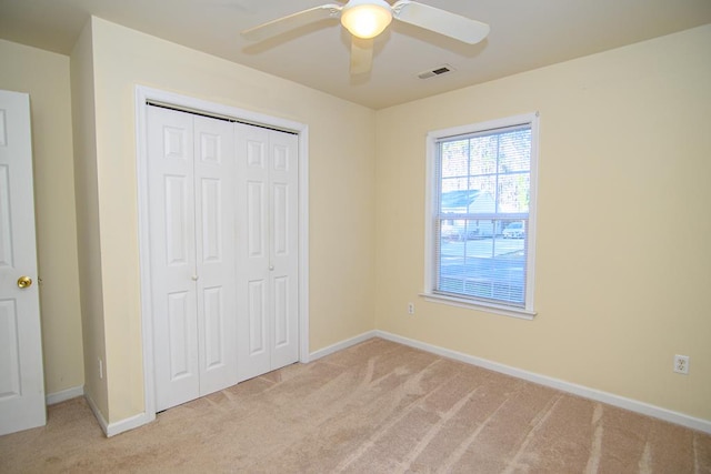 unfurnished bedroom featuring ceiling fan, light carpet, and a closet