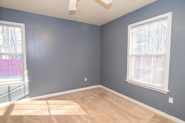 empty room with a wealth of natural light, ceiling fan, and light colored carpet