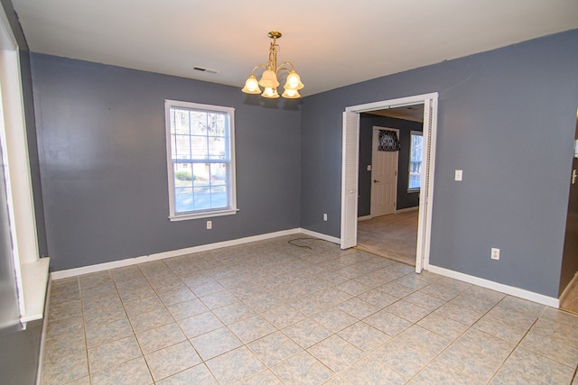 tiled spare room featuring a chandelier