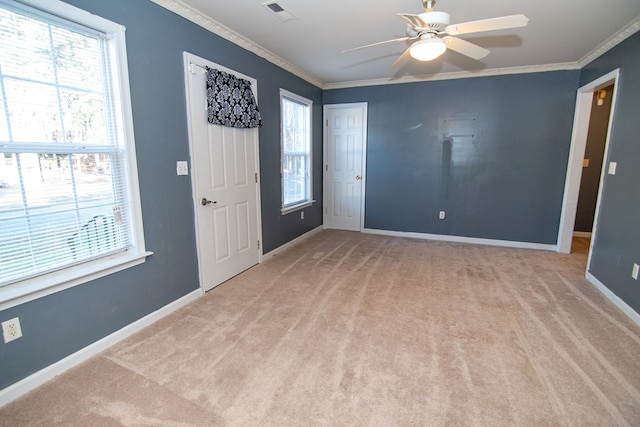 foyer featuring ceiling fan, light colored carpet, crown molding, and a wealth of natural light