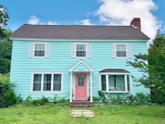 3250 Colona St, Chincoteague, VA 23336 - colonial house featuring a chimney, a front lawn, and a shingled roof