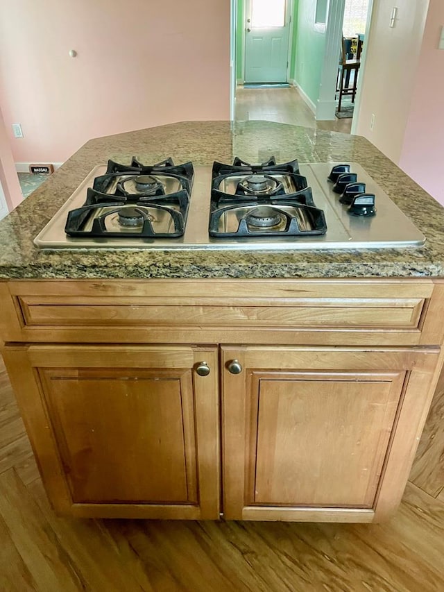 3250 Colona St, Chincoteague, VA 23336 - kitchen view of gas stovetop, wood finished floors, brown cabinetry, and light stone counters