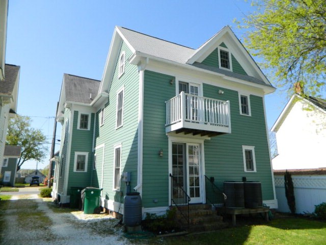 back of property with a balcony and entry steps