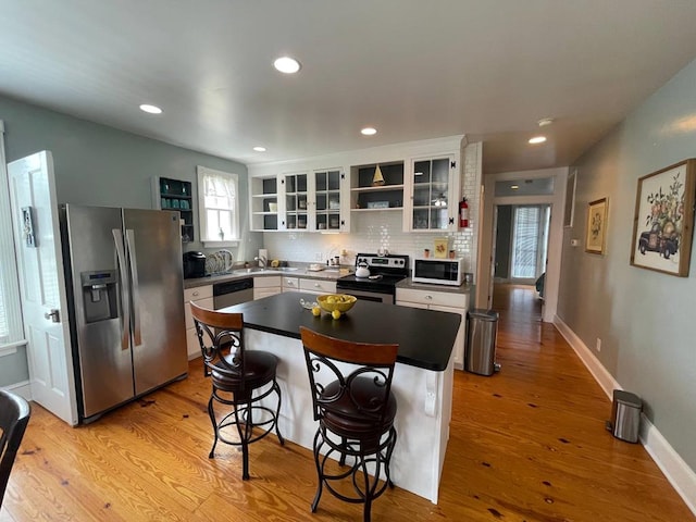 405 Randolph Ave, Cape Charles, VA 23310 - kitchen with a center island, open shelves, decorative backsplash, appliances with stainless steel finishes, and light wood-style floors