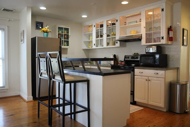 405 Randolph Ave, Cape Charles, VA 23310 - kitchen featuring under cabinet range hood, stainless steel range with electric stovetop, a kitchen bar, black microwave, and open shelves