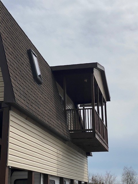 view of home's exterior featuring a balcony and roof with shingles