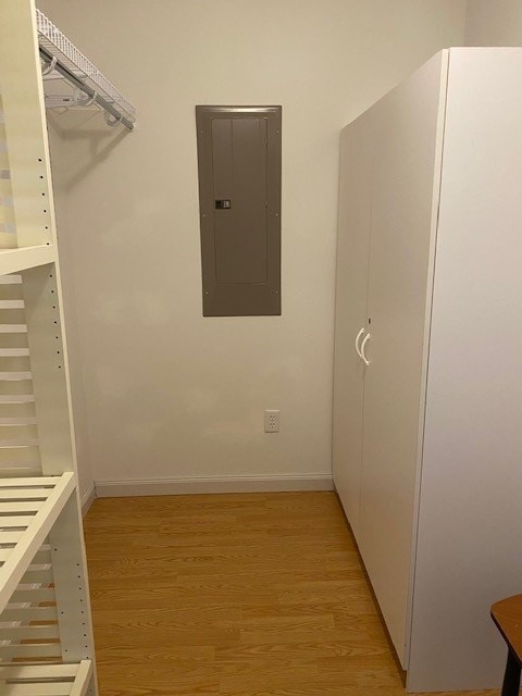 walk in closet with electric panel and light wood-type flooring