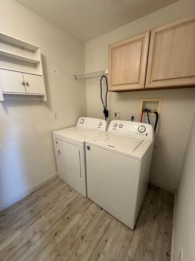 laundry room with cabinet space, baseboards, light wood finished floors, and washing machine and clothes dryer