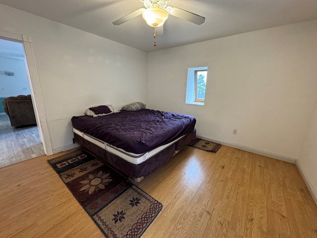 bedroom featuring ceiling fan, baseboards, and wood finished floors