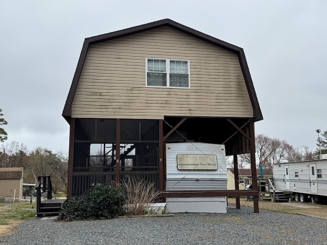 view of front facade with a gambrel roof and a sunroom