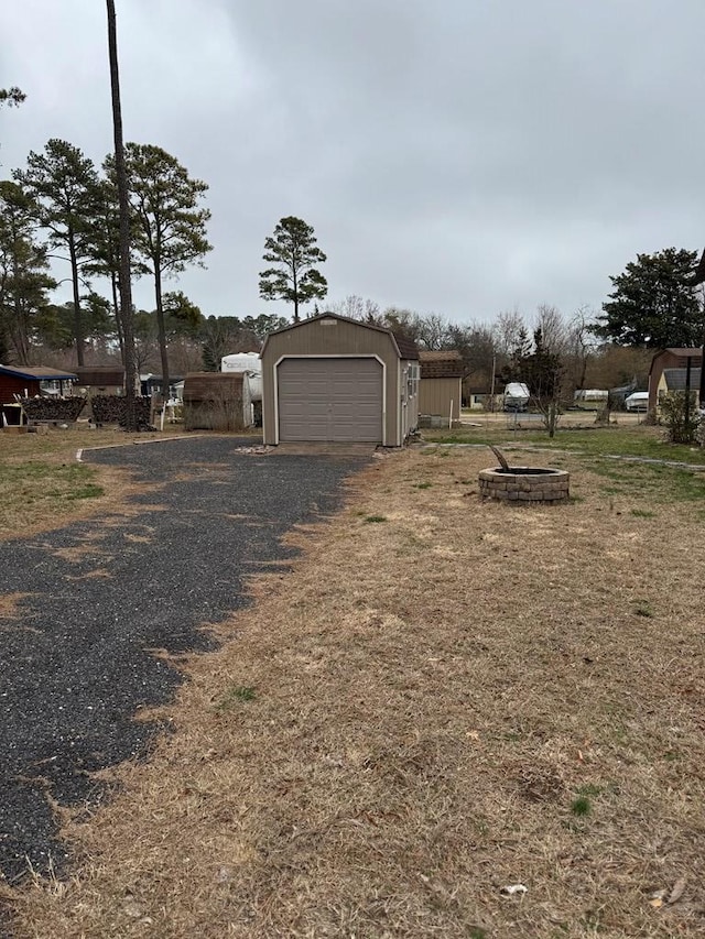 view of yard featuring an outdoor structure, driveway, and a detached garage