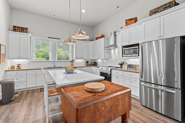 8 Perny Ct, Cape Charles, VA 23310 - kitchen with stainless steel appliances, a kitchen island, light wood-style flooring, and wall chimney exhaust hood