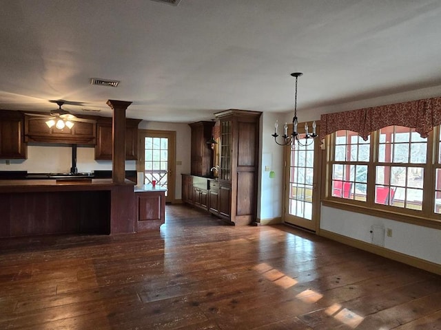 kitchen with dark wood-style floors, dark countertops, visible vents, glass insert cabinets, and baseboards