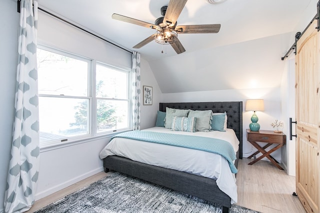 bedroom with multiple windows, hardwood / wood-style flooring, vaulted ceiling, and ceiling fan