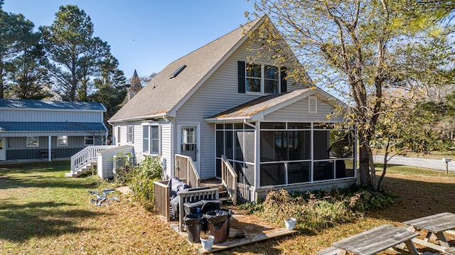 rear view of property featuring a sunroom and a yard