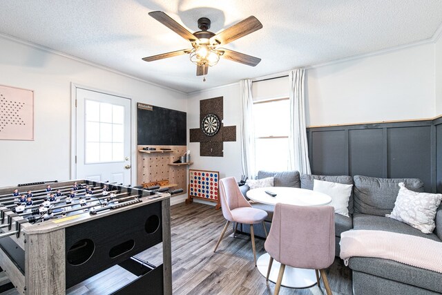 playroom featuring ceiling fan, light wood-type flooring, a textured ceiling, and ornamental molding