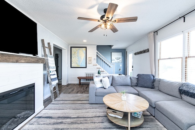 living room with crown molding, ceiling fan, a textured ceiling, and hardwood / wood-style flooring