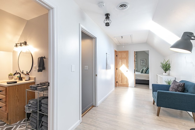 hallway with vaulted ceiling and light hardwood / wood-style flooring