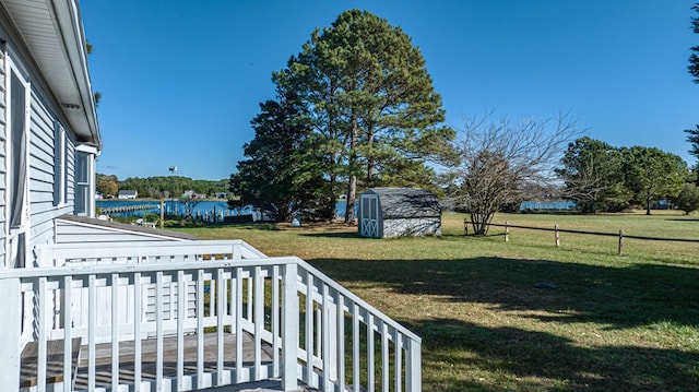 view of yard with a storage unit and a deck with water view