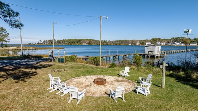 view of yard with a water view, a fire pit, and a boat dock