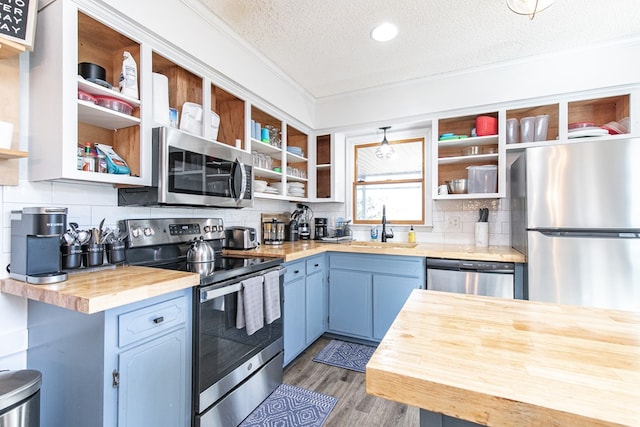 kitchen featuring sink, stainless steel appliances, tasteful backsplash, butcher block countertops, and a textured ceiling