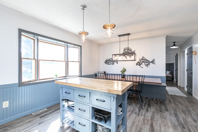 kitchen with pendant lighting, a center island, butcher block counters, and a textured ceiling