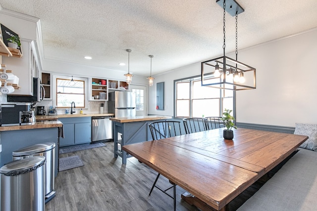 dining space featuring a textured ceiling, crown molding, sink, and hardwood / wood-style flooring