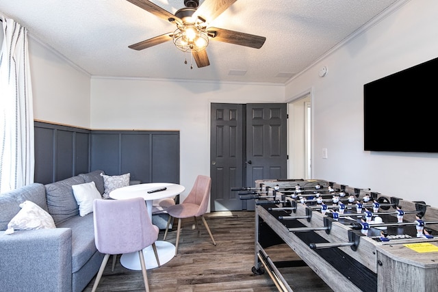 living room with ceiling fan, dark hardwood / wood-style floors, a textured ceiling, and ornamental molding