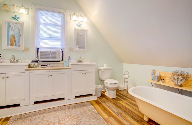 bathroom featuring toilet, vanity, hardwood / wood-style flooring, and vaulted ceiling